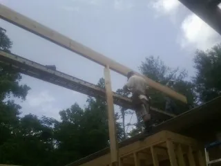 Carpenter setting a ridge beam over a new addition frame — Ice Dam Removal by Roofing Brothers in Fergus Falls