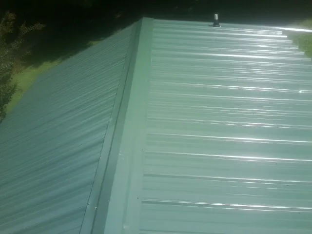 New green metal panels meeting at the ridge of a roof — Flat Roof Repair work by our crew in Fergus Falls