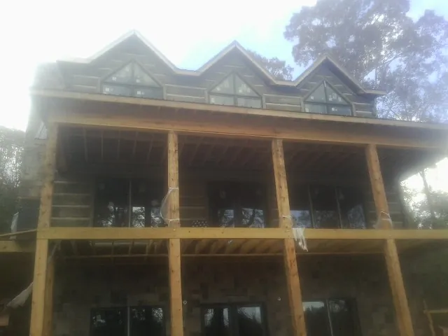 Dormers and porch framing on a large log home under construction — Roof Coating work by our crew in Fergus Falls