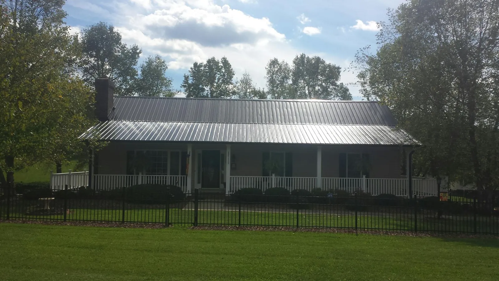 Gray metal roof on a brick ranch with a full width front porch — Gutter Guard Installation work by our crew in Fergus Falls