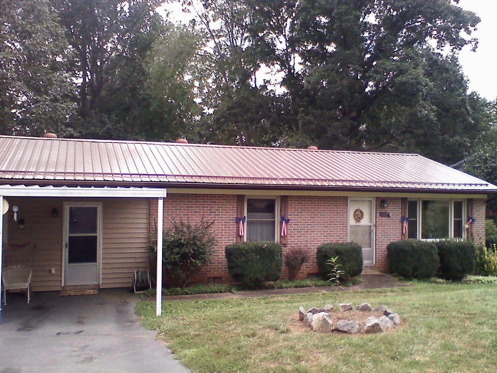 Bronze metal roof and carport on a brick ranch home — Roof Repair work by our crew in Fergus Falls
