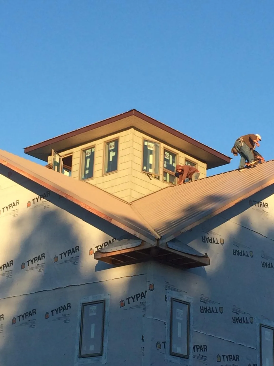 Roofers working around a rooftop cupola on a new metal roof at sunset — Roof Waterproofing in Fergus Falls by Roofing Brothers